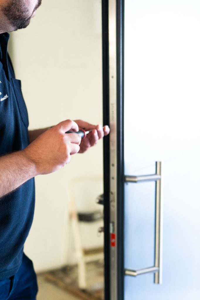 Un homme qui met en place une porte blindée et qui utilise un tournevis