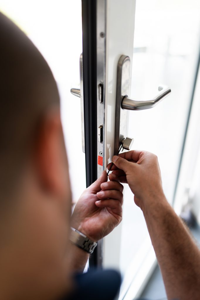 Un homme ajuste le mécanisme de verrouillage d’une porte.