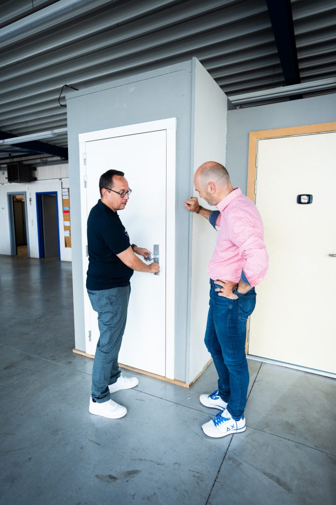 Deux hommes qui discutent devant une porte blindée